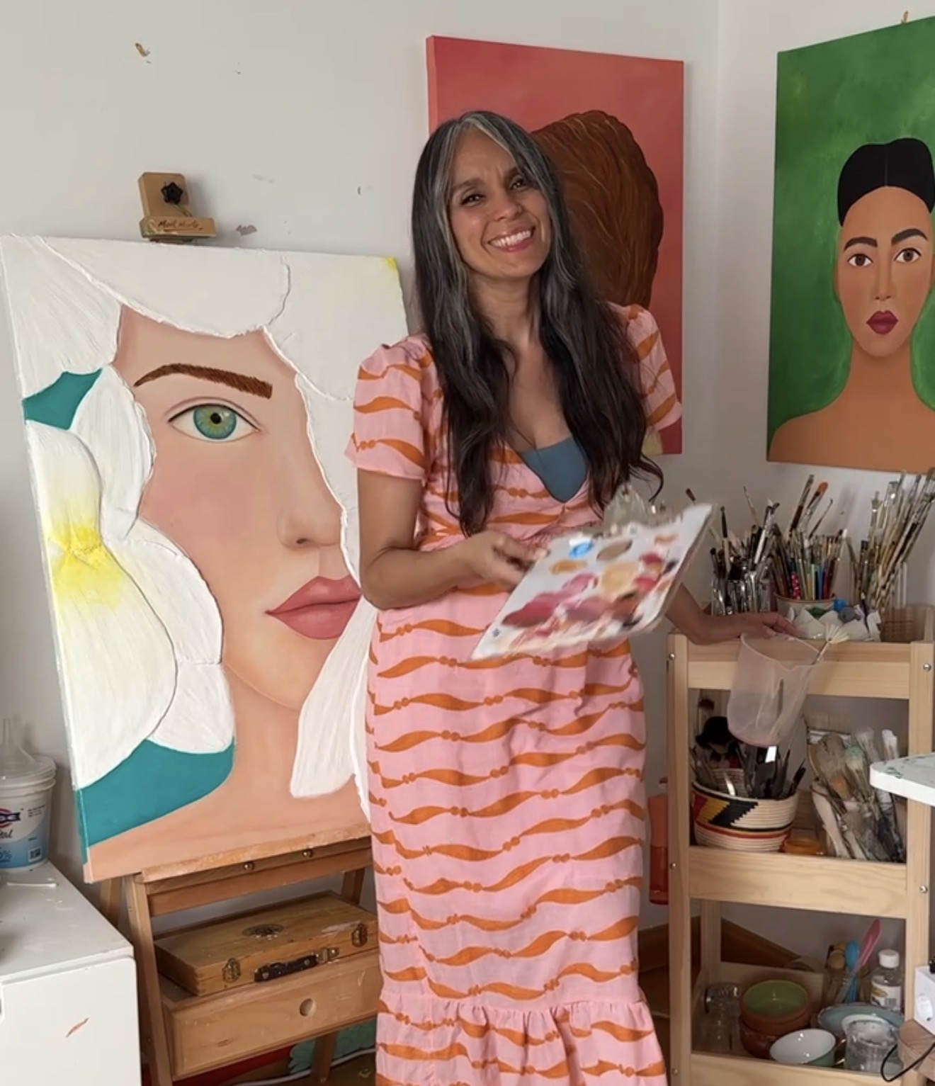 Inmita, la artista, en su estudio junto a un retrato al óleo en proceso