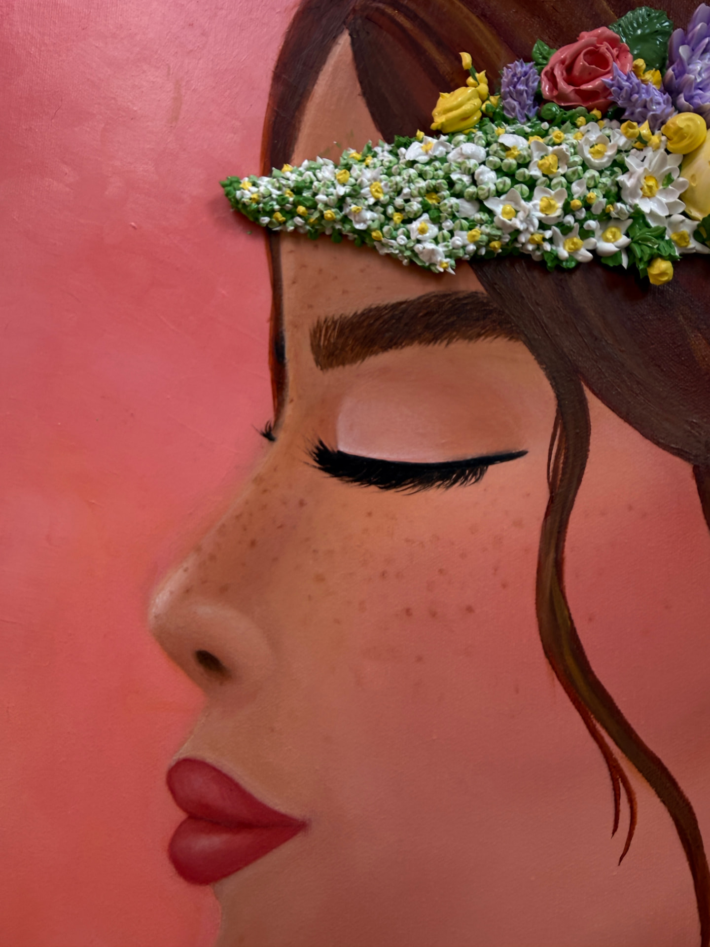 Detalle del rostro pintado al óleo con la corona de flores modeladas a mano en relieve